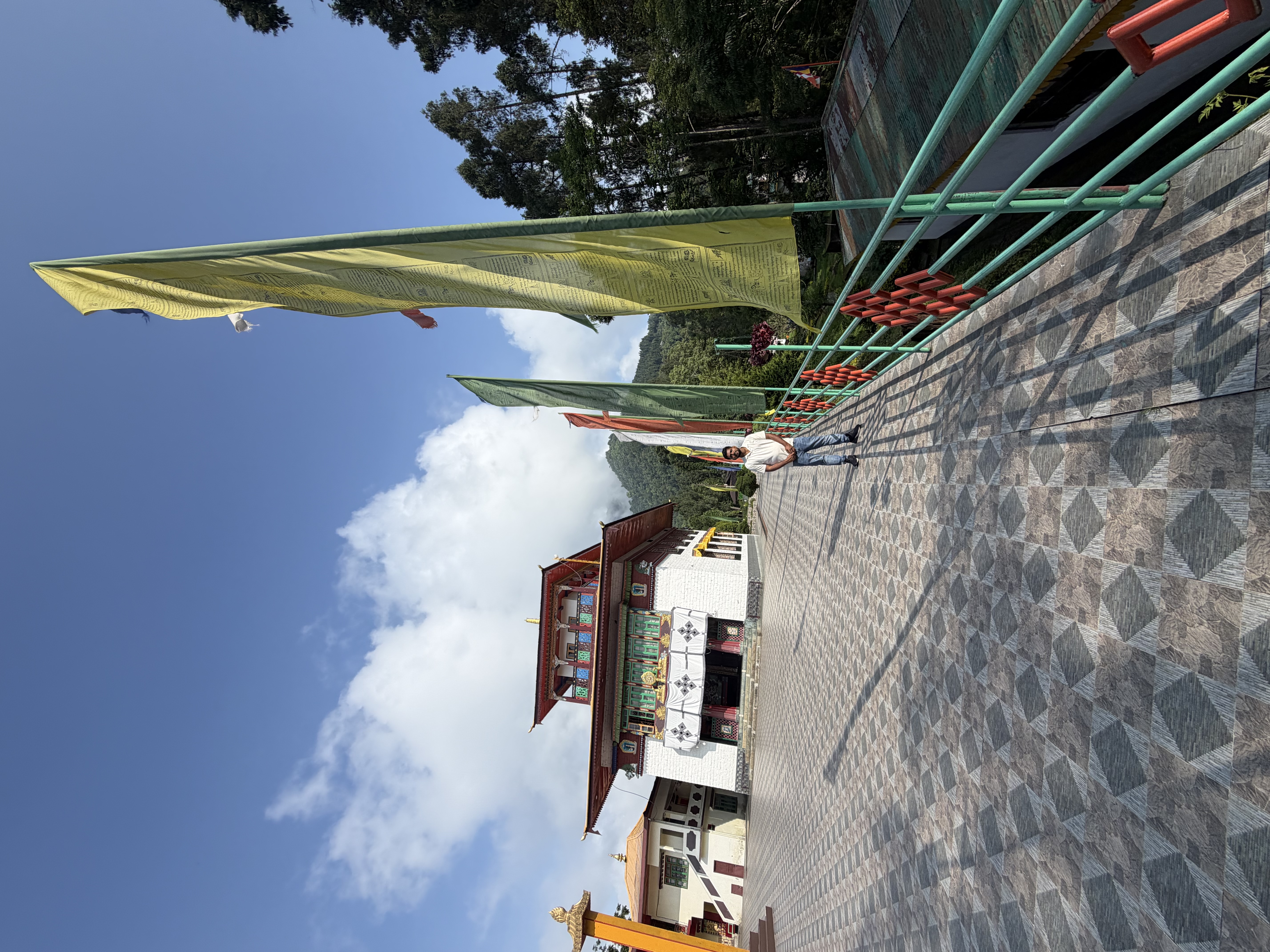 Rumtek Monastery courtyard with colourful prayer flags against a blue Sikkim sky